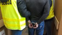 zdjęcie przedstawiające policjantów prowadzących osobę zatrzymaną w kajdankach