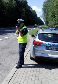policjant dokonujący pomiaru prędkości na drodze