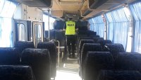 policjant sprawdza wyposażenie wewnątrz autobusu szkolnego