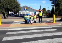 Policjant przeprowadza dzieci przez przejście dla pieszych