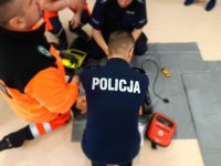 Policjant ćwiczący pierwszą pomoc na fantomie przy użyciu AED, ratownicy medyczni