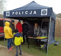 Punkt informacyjny Policji - namiot z napisem Policja, policjant, pracownik cywilny, osoby postronne
