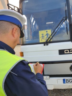 policjant pisze dokumentacje podczas kontroli autobusow
