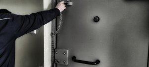 drzwi policyjnej  celi zamykane na łańcuch przez policjanta