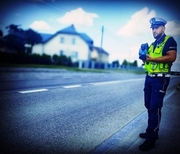policjant stojący przy ulicy z urządzeniem do mierzenia prędkości