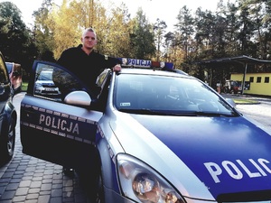 umundurowany policjant stojący przy radiowozie