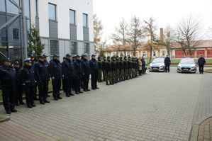 Pododdział Policji, klasa mundurowa, w tle dwa radiowozy a przy nich dwaj policjanci