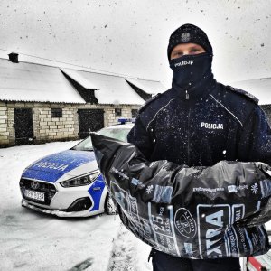 Policjant, worek z węglem, w tle radiowóz