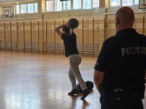policjant na sali gimnastycznej oraz kobieta rzucająca piłką